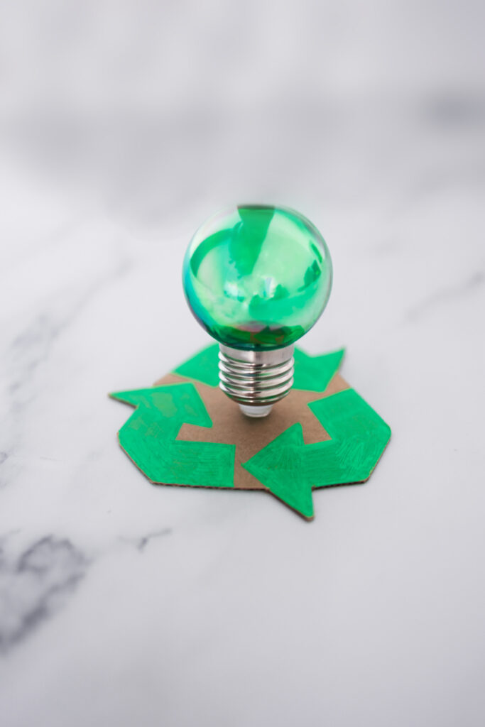 recycle sign with green light bulb standing on it, concept of sustainability and circular economy